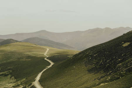 landscape road between mountains and green valley at sunsetの写真素材