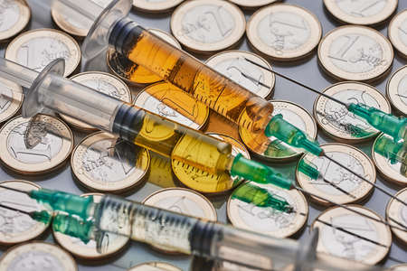 syringes on a mountain of money. covid vaccine. High quality photoの写真素材