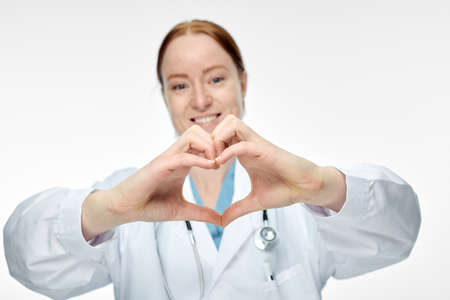 young smiling female doctor making heart sign with her handsの写真素材