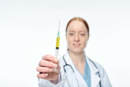 young female doctor shows syringe with forehead vaccineの写真素材