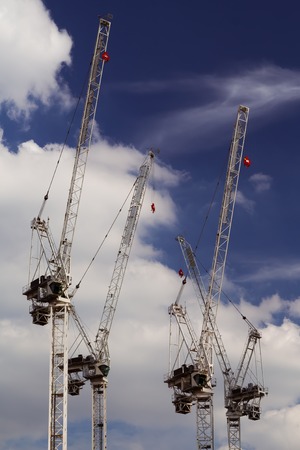 Multiply tower cranes with blue deep blue sky and white clouds in the background, on a building site...