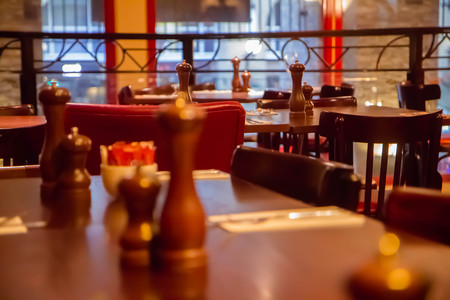 A black and white photograph of a hoop backed chair next to a table with a white table cloth set with cutlery.の写真素材