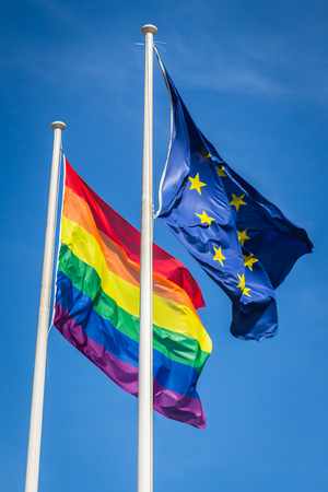 Rainbow flag and EU flag waving in the wind, sunny day, blue skyの写真素材