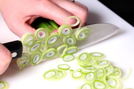 Female hands cutting green onionの写真素材