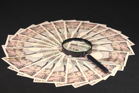 Ten thousand japanese yen bills and magnifying glassの写真素材