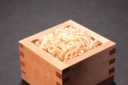 Dried shrimp in a wooden cup on black background