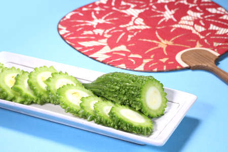 Sliced bitter gourd on a plate and japanese fan