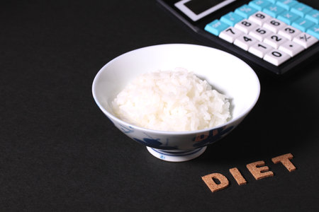 Diet image. rice in a bowl, calculator and  cork letters of DIETの写真素材