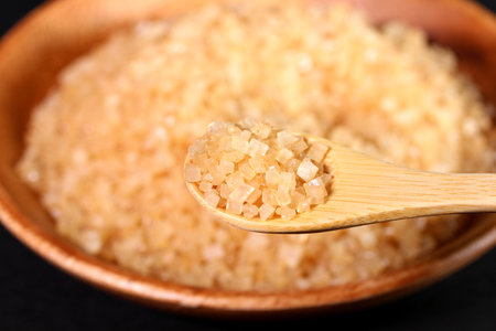 Scooping brown cane sugar with a wooden spoonの写真素材