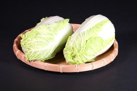 Mini chinese cabbage on a colander on black backgroundの写真素材