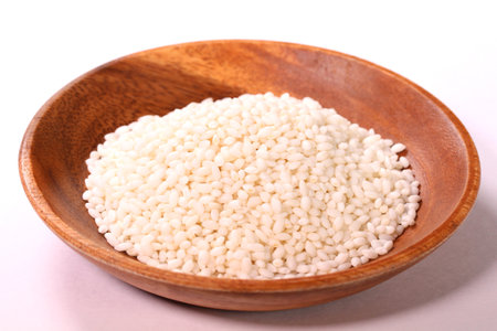 Uncooked japanese sticky rice on a wooden bowl on white backgroundの写真素材