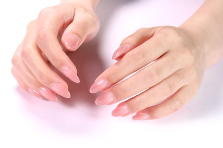 Female hands with pale pink manicure on nails, isolated on whiteの写真素材