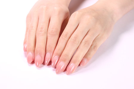 Female hands with pale pink manicure on nails, isolated on whiteの写真素材
