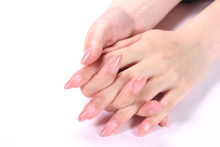 Female hands with pale pink manicure on nails, isolated on whiteの写真素材