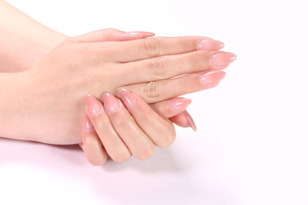 Female hands with pale pink manicure on nails, isolated on whiteの写真素材