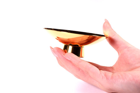 Female hand holding a gold cup on white backgroundの写真素材
