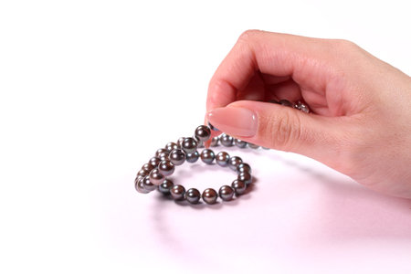Female hand holding a black pearl necklaceの写真素材