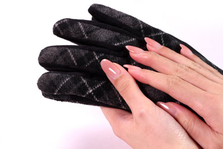 Female hand holding black gloves on white backgroundの写真素材