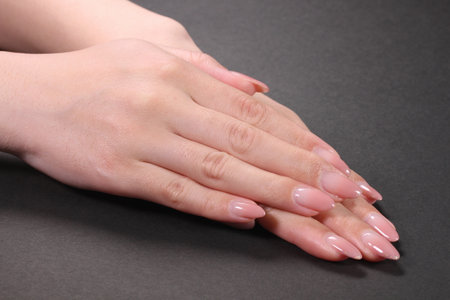 Female hands with pale pink manicure on nails, isolated on blackの写真素材