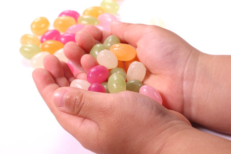 Colorful jelly beans in the child's hands on white backgroundの写真素材