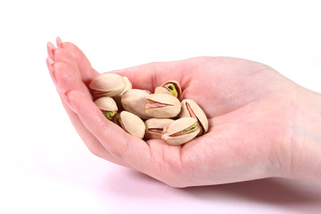 Pistachio nuts in woman's hand isolated on white backgroundの写真素材