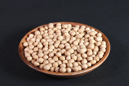 soy beans in a wooden bowl on a black background closeupの写真素材
