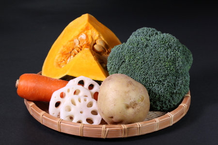 Fresh vegetables on a bamboo colander on black background.の写真素材