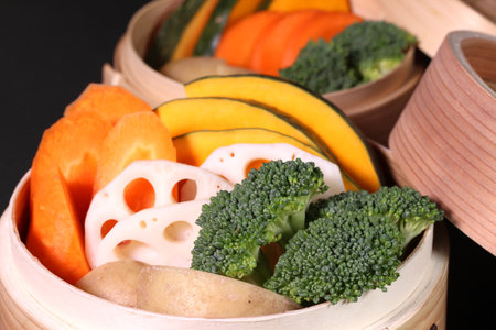 Fresh vegetables in bamboo steamer on black backgroundの写真素材