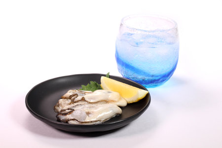 Fresh oysters and a glass of  shochu on white backgroundの写真素材