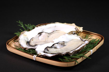 Fresh oysters on a bamboo colander on black backgroundの写真素材