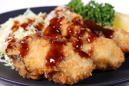 Deep fried oysters with sauce on a black plateの写真素材
