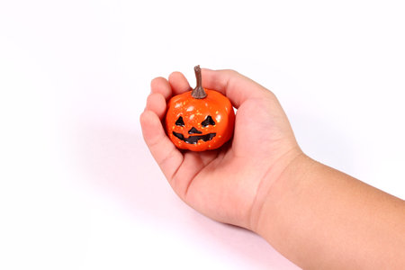Child's hand holding a haunted pumpkin decorationの写真素材