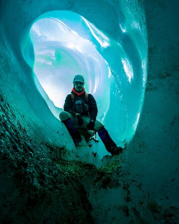 Man inside an ice cave. Excursion on a glacier. Vertical photographyの写真素材