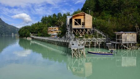 Typical architecture of Caleta Tortel.There are wooden galleries that connect the entire population. You can see a boat on a dock and some houses on the coast of the Pacific Ocean. Patagonia, Chileの写真素材
