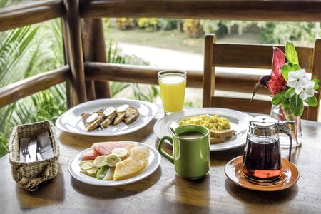 Delicious American Breakfast with coffee, orange juice, fresh fruits, eggs and french toasts. Outdoor hotel restaurantの写真素材
