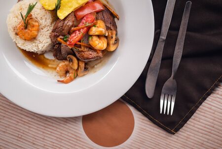 Strips of beef and shrimps with potatoes and red pepper served with a terrine of rice. Top viewの写真素材
