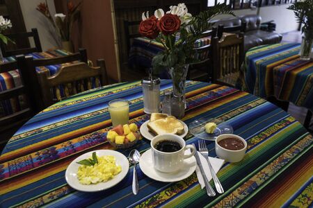 Breakfast consisting of coffee, sweet, butter, orange juice, toast, and fresh fruitsの写真素材