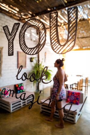 Woman unfocused reflected in the mirror. In the mirror says: "you look amazing!"の写真素材