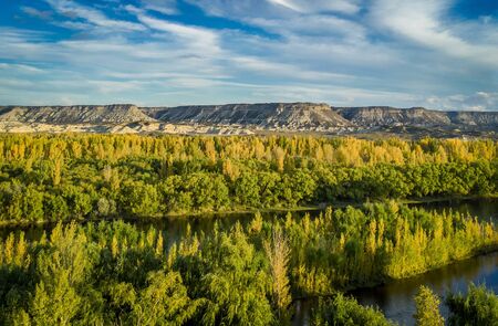 Landscape of a valley in autumn. There is a huge river and big mountain cliff behind. General Roca, RÃ­o Negro - Patagonia Argentinaの写真素材