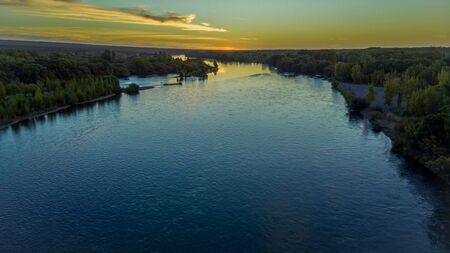 Sunset at a river, during autumn on a valley. You can see the huge river passing by, the sun behind...