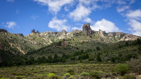 Mountain of rocky peaks, background of blue sky and white clouds. You can see a valley full of vegetation and very colorful. Villa Traful, Patagonia Argentinaの写真素材
