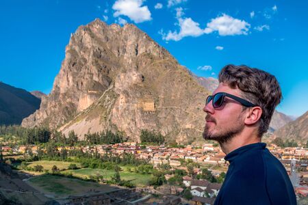 A man tourist in profile with sun glasses, with the background of the city of Ollantaytambo, Sacred Valley of the Incas.の写真素材