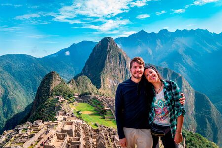 Young couple of tourist in Machu Picchu. They are together, happy and relaxed. Behind, The City of Machu Picchu and the Huayna Picchu Mountain.の写真素材
