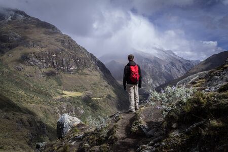 A person appreciating the landscape in the heights. There are small bushes around it and huge mountains and clouds. Latin Americaの写真素材