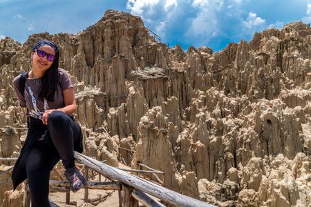 A tourist woman posing in the Moon Valley in La Paz, Bolivia. Many clay peaks can be seen on the backgroundの写真素材