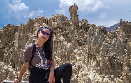 A tourist woman posing in the Moon Valley in La Paz, Bolivia. Many clay peaks can be seen on the backgroundの写真素材