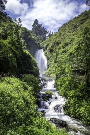 View of Peguche Waterfall in the mountains of Ecuador. There is a huge waterfall surrounded by a lot of vegetationの写真素材