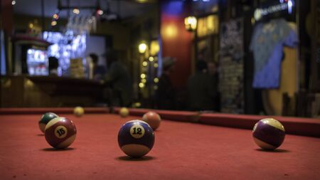 Pool table with several separated balls. You can see ball 12 and 15. In the background you see people having drinks in what looks like a barの写真素材