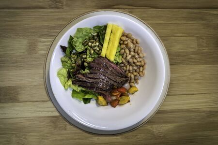 Beef with beans, grilled vegetables and salad on a wooden background. Top viewの写真素材