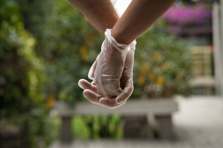 Hands holding each other wearing sanitary gloves. Close up. COVID-19 conceptの写真素材